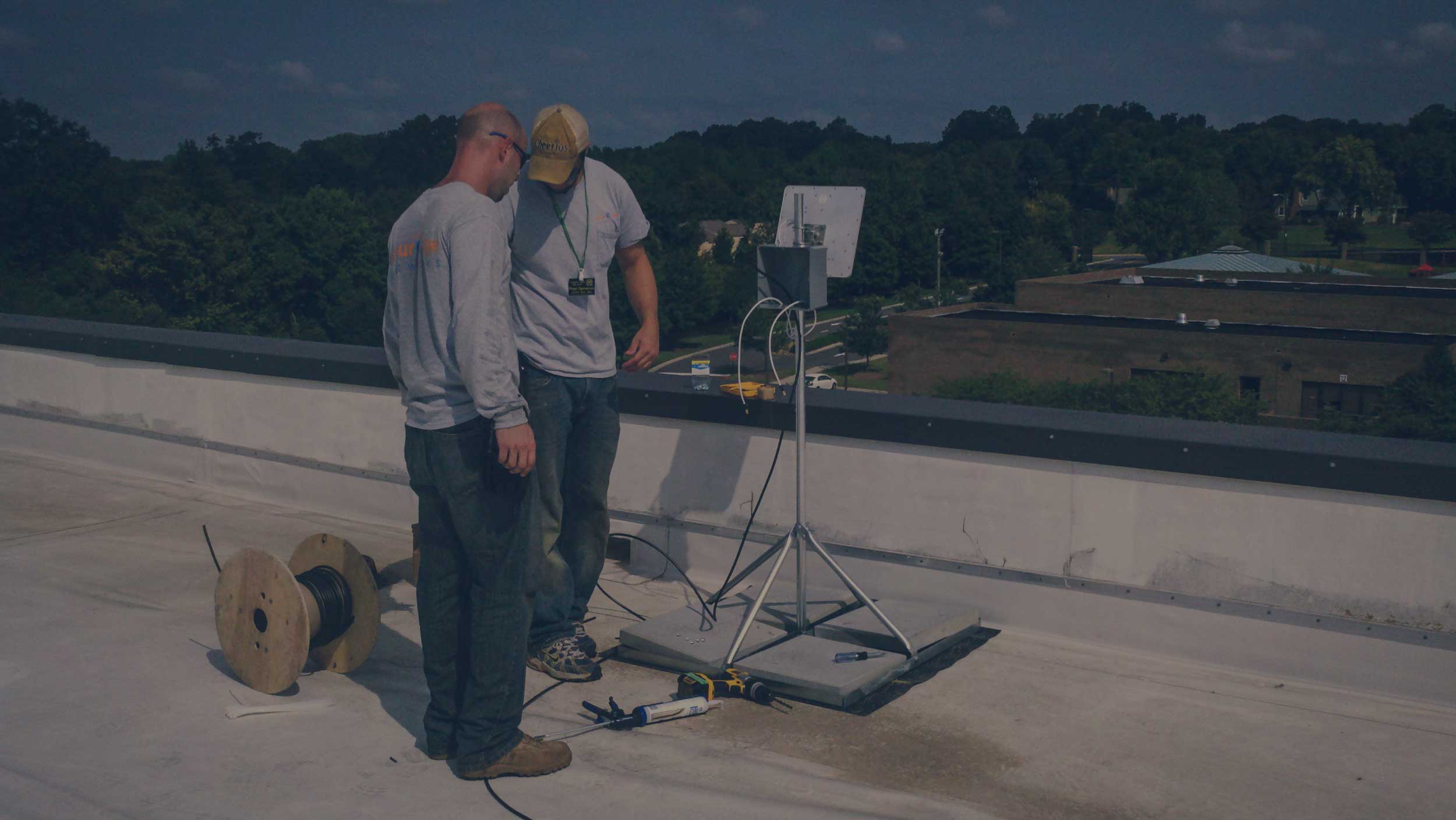 two network engineers on roof of building installing equipment